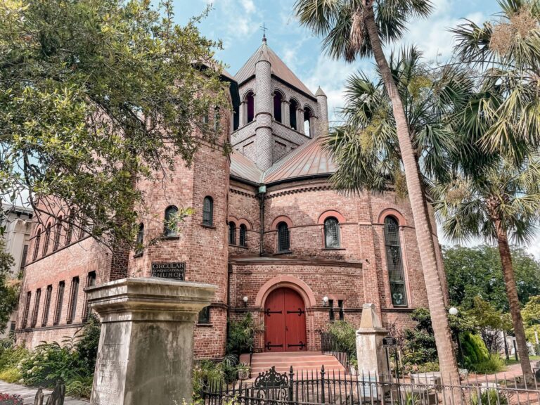 Circular church behind iron fence with trees around it for why is Charleston called The Holy City