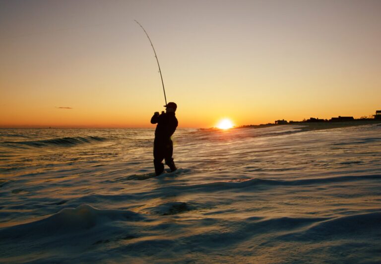 Man pulling in a fish while fishing in the water at sunset while on fishing trips in Charleston SC